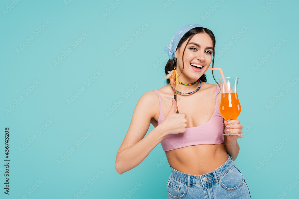 Smiling woman with cocktail showing like gesture isolated on blue. Smiling woman with cocktail showing like gesture isolated on blue.