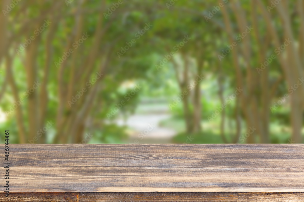 wood table top on blur green alley of trees background wood table top on blur green alley of trees background