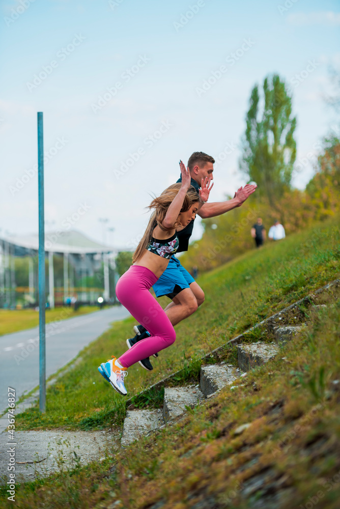 Young man and young woman with a healthy lifestyle jumping in the stairs outdoors