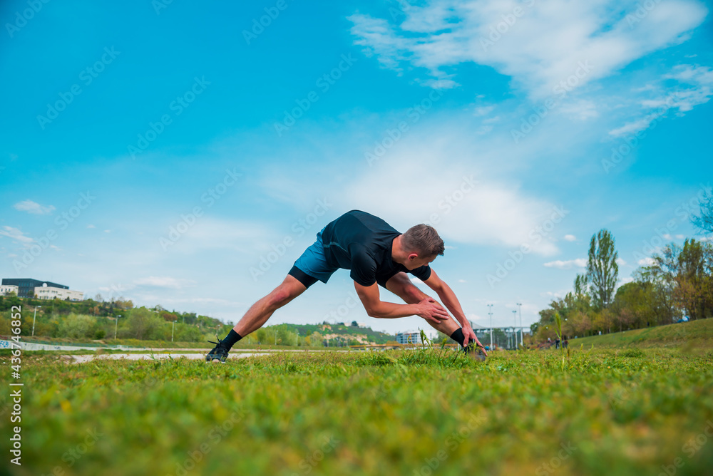 Caucasian young man stretching after outdoor jogging Caucasian young man stretching after outdoor jogging
