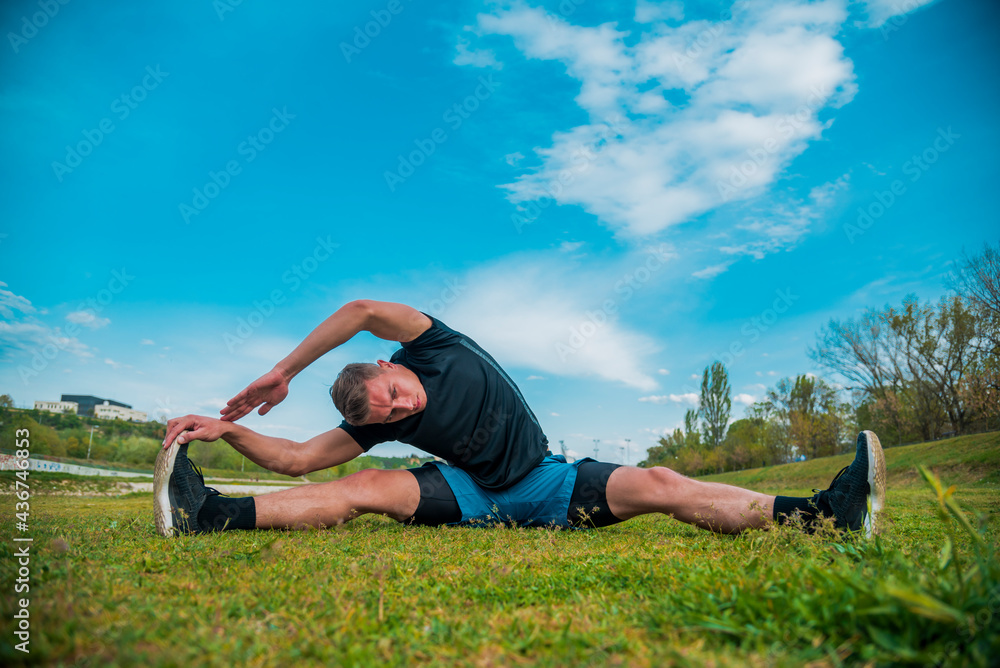 Young sportive man doing exercise before running in morning field outdoors Young sportive man doing exercise before running in morning field outdoors