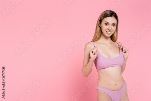Smiling pretty woman in swimwear looking at camera isolated on pink. © LIGHTFIELD STUDIOS