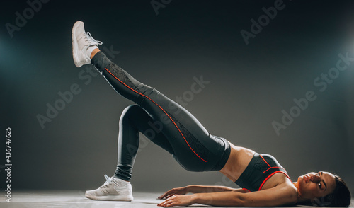 Studio shot of beautiful sporty girl stretching isolated on dark