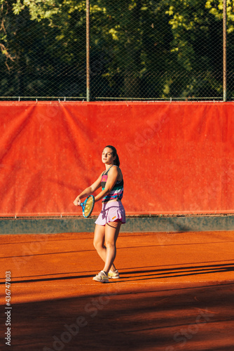 Pretty sportswoman with racquet playing tennis on a sunny day