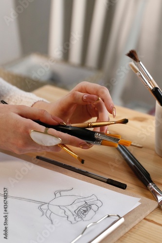 Woman artist's hand with brushes and unusual ring accessory
