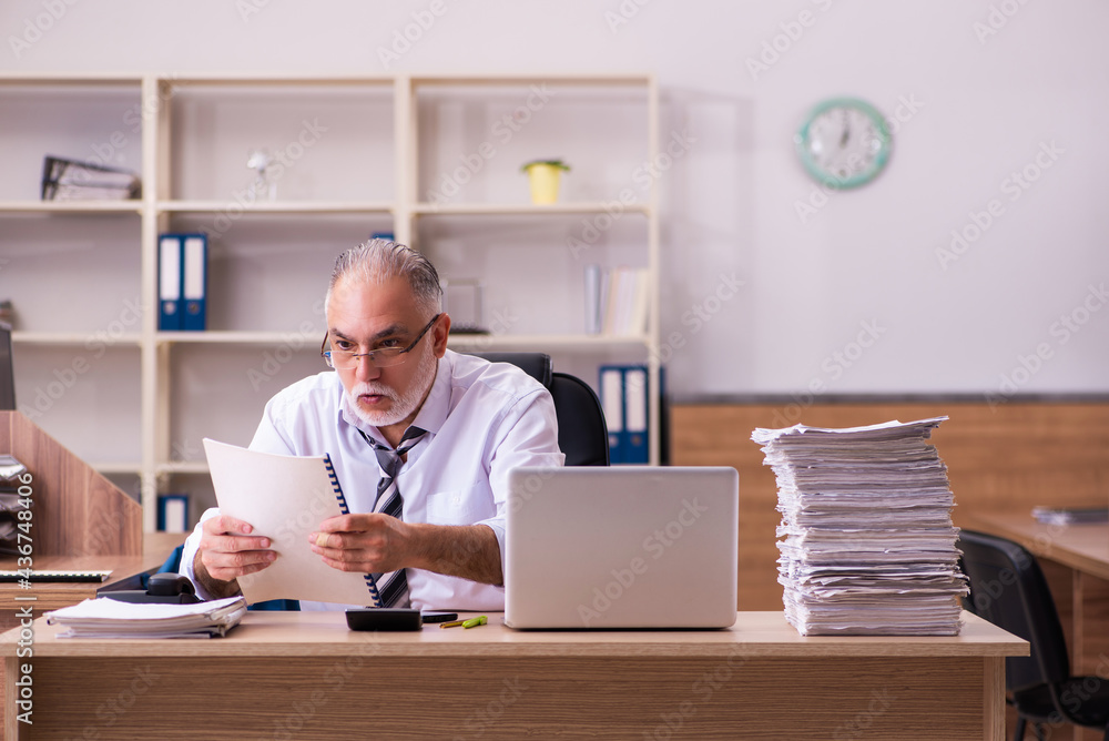 Old male employee unhappy with excessive work in the office Old male employee unhappy with excessive work in the office