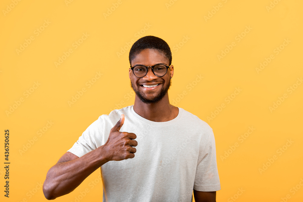 I like it. Joyful black man gesturing thumb up, approving and recommending something over yellow background, studio shot I like it. Joyful black man gesturing thumb up, approving and recommending something over yellow background, studio shot