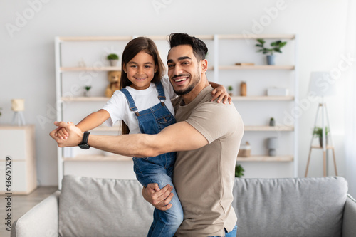 Dad and daughter dancing in living room together