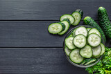 Cucumber on  dark wood texture background.Cucumbers harvest in summer. Cucumbers for salads or canning. Summer vegetables.Slices of fresh cucumbers in a bowl.