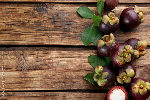 Fresh ripe mangosteen fruits on wooden table, flat lay. Space for text