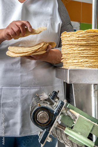 machine to make tortillas Mexican tortilleria with metal band and a kilo of tortillas wrapped in white paper photo