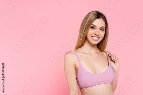 Pretty woman in swimsuit smiling at camera isolated on pink.
