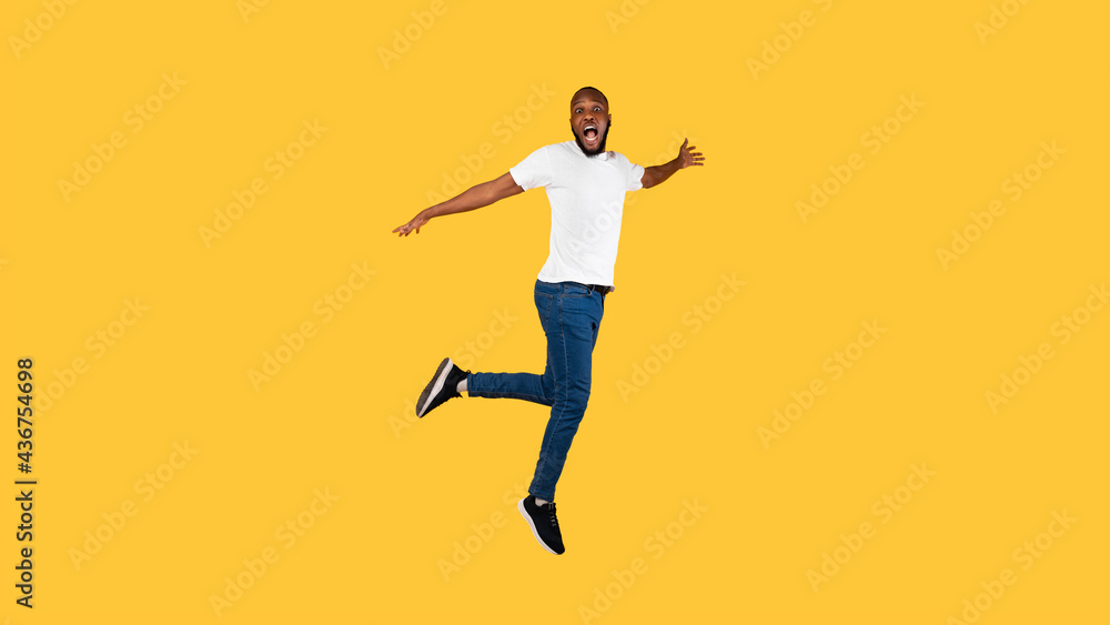 Shocked African American Guy Jumping Looking At Camera, Yellow Background