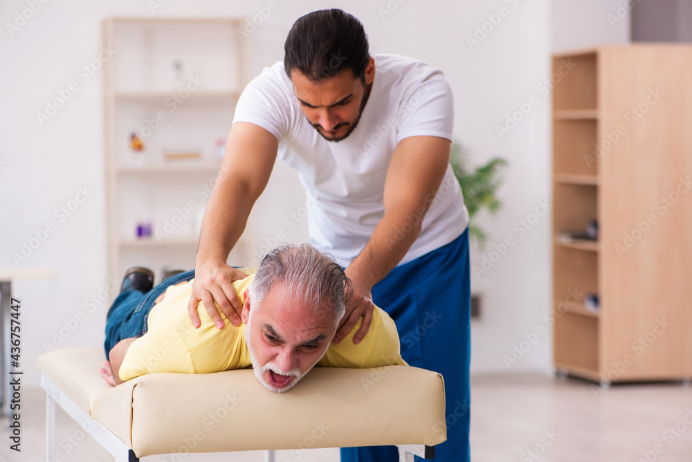 Fototapeta premium Old male patient visiting young male doctor chiropractor