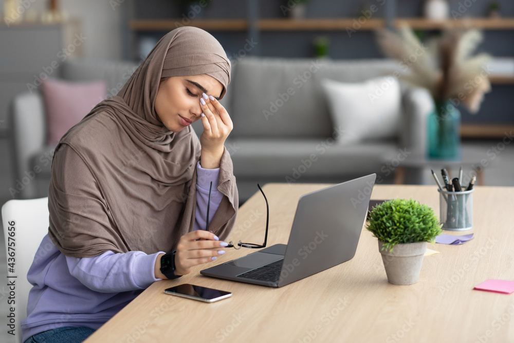 Tired muslim woman sitting at desk, rubbing dry irritated eyes - obrazy, fototapety, plakaty 