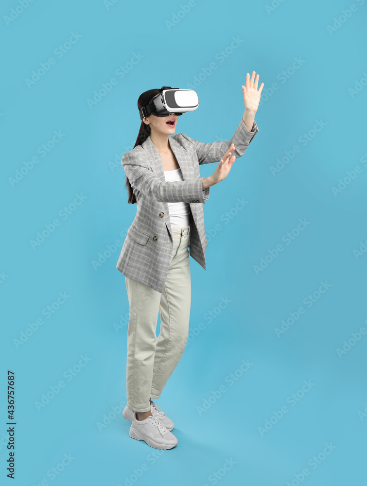 Woman using virtual reality headset on light blue background Woman using virtual reality headset on light blue background