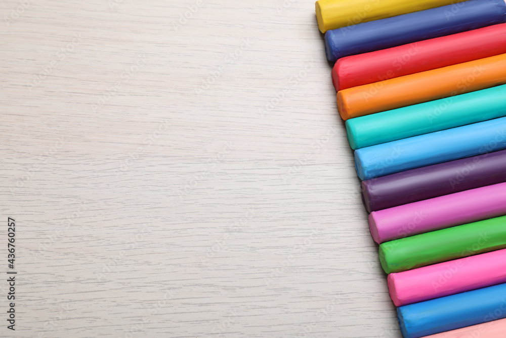 Fototapeta premium Pieces of colorful plasticine on wooden table, flat lay. Space for text
