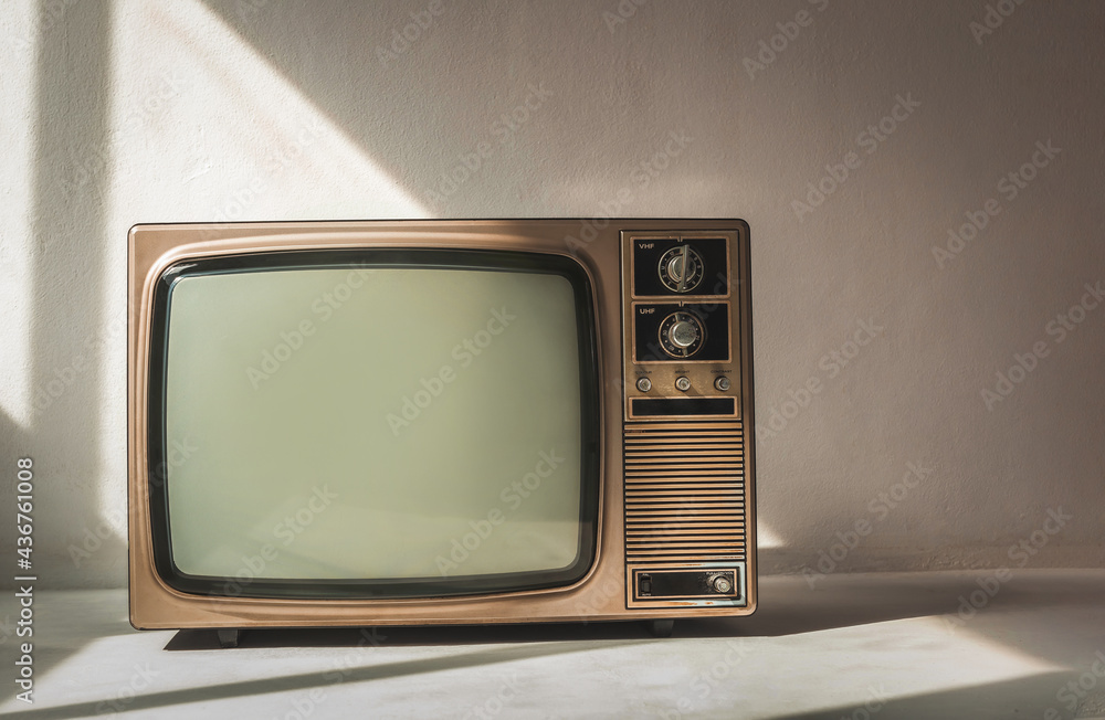 Retro old television with empty screen on cement floor in a white room. Vintage TV technology, front view