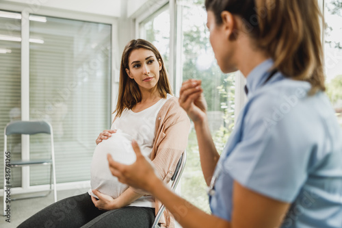 Pregnant Woman Talking To Gynecology Nurse At Waiting Room
