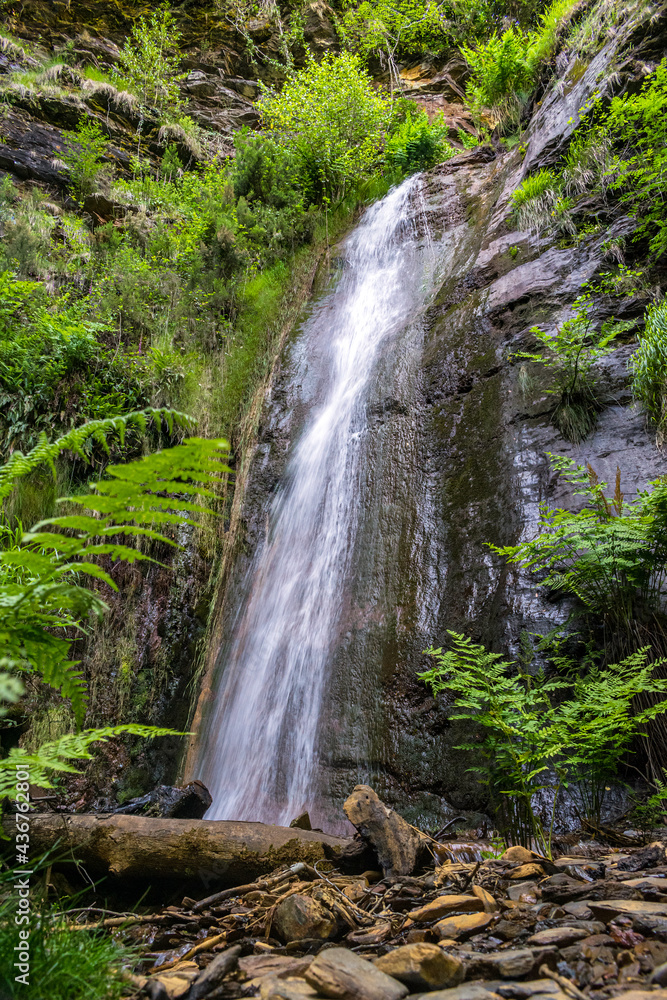 Obraz premium Water flows through a mountain waterfall