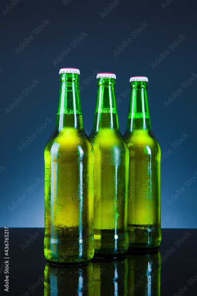 green beer bottle with drops on blue background green beer bottle with drops on blue background