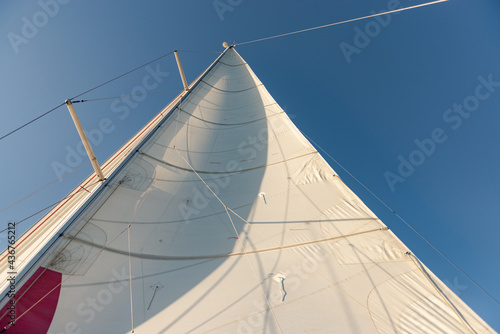 Sail mainsail on a yacht. Sail on a yacht filled with wind. Photo from the side of the yacht up.