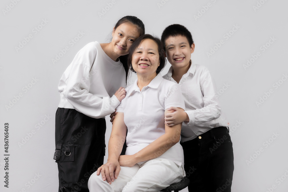 Portrait of Grandmother and grandchild hugging, looking at camera and smiling, on gray background Portrait of Grandmother and grandchild hugging, looking at camera and smiling, on gray background