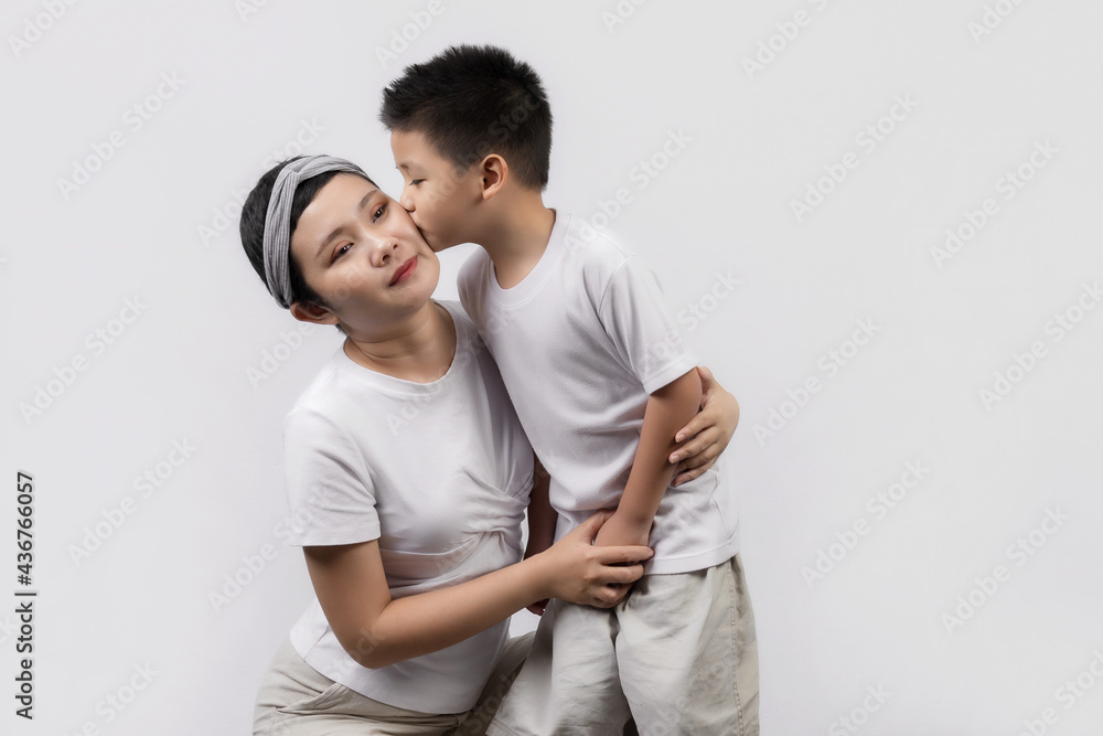 Young adult female cancer patient spending time with little son on gray background. Cancer and family support concept. Young adult female cancer patient spending time with little son on gray background. Cancer and family support concept.