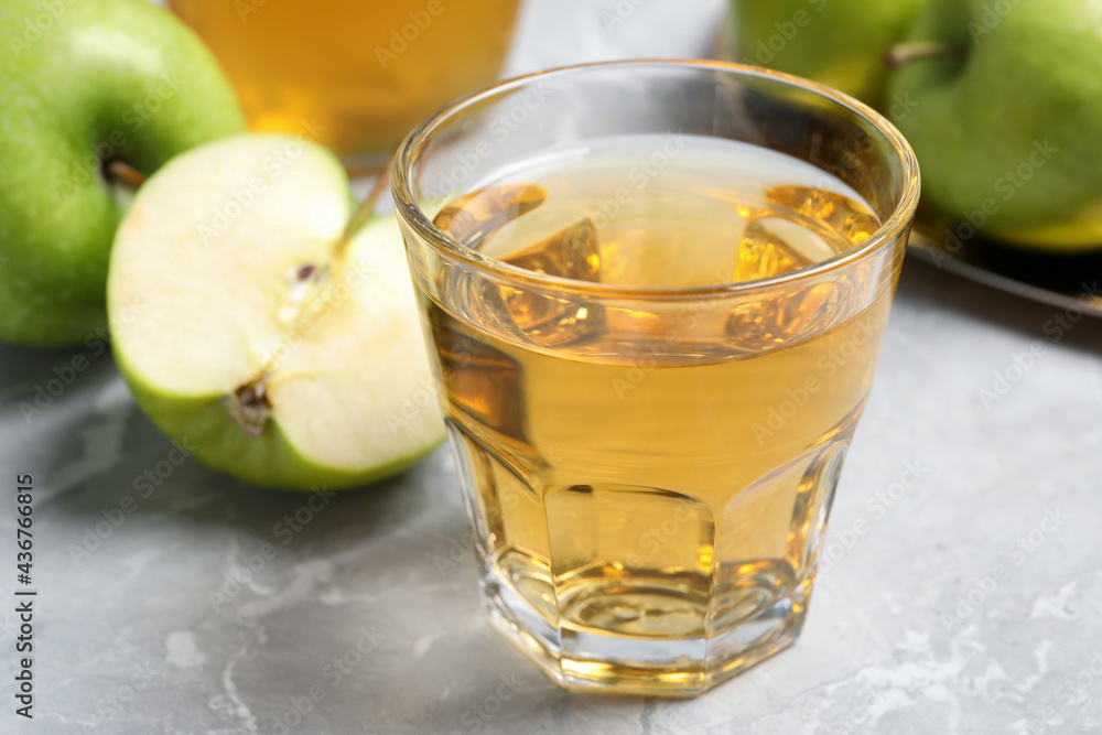 Glass of fresh juice and apples on grey table, closeup Glass of fresh juice and apples on grey table, closeup