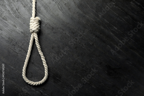 Rope noose on black table, top view. Space for text