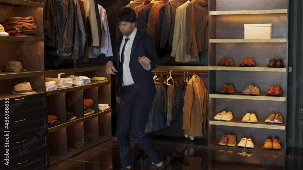 Smiling man dances in a modern suit in the dressing room. A man celebrates success in business Smiling man dances in a modern suit in the dressing room. A man celebrates success in business