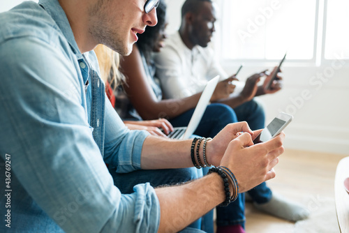 Group of diverse friends hanging out and using digital devices