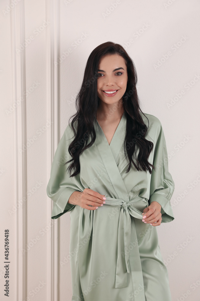 Pretty young woman in beautiful light silk robe near white wall Pretty young woman in beautiful light silk robe near white wall