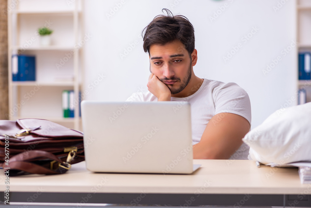 Young male employee coming to work straight from bed Young male employee coming to work straight from bed
