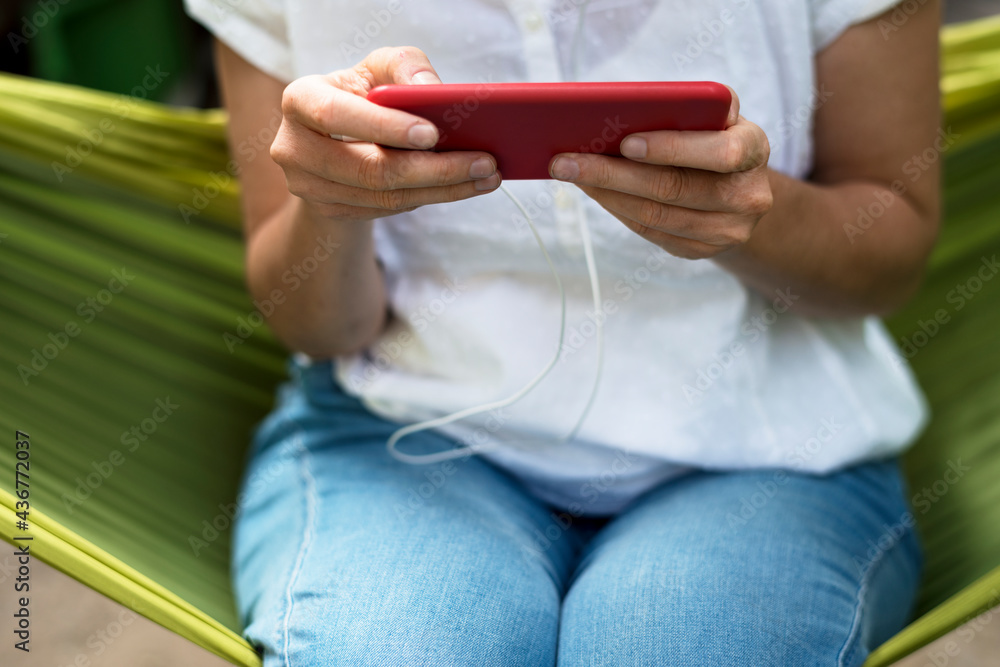 An Adult Woman Using Mobile Phone on a Hammock An Adult Woman Using Mobile Phone on a Hammock