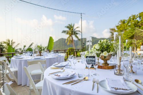 Romantic Wedding Table Top Layout Table Spread no people tropical location with gold cutlery white table cloth and scenic view of sunset with copy space tablescape, beautiful paradise setting