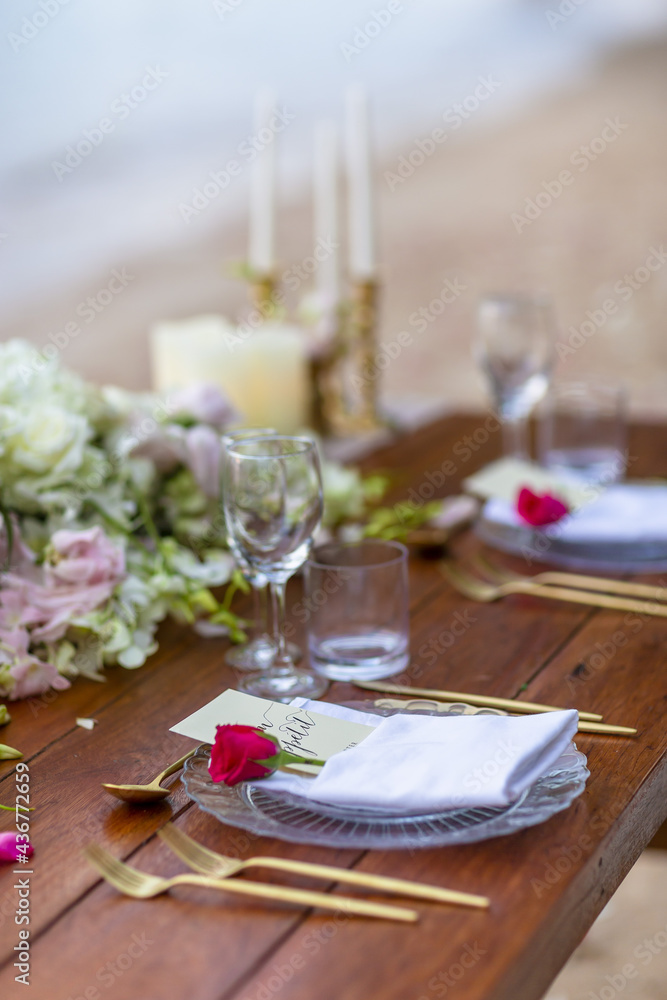 Romantic Wedding Table Top with Red Roses Layout Table Spread no people tropical beach location with gold cutlery and scenic view of sunset on the beach soft light