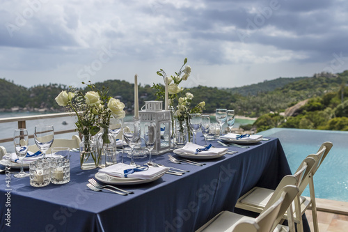 Fototapeta Naklejka Na Ścianę i Meble -  Blue and Silver Romantic Wedding Table Top Layout Table Spread no people catering, event, decor in a tropical location with the sea and clouds in the background