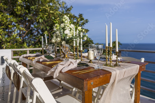 Fototapeta Naklejka Na Ścianę i Meble -  Romantic Wedding Table Top Layout Table Spread no people tropical location with gold cutlery and scenic sea view with copy space