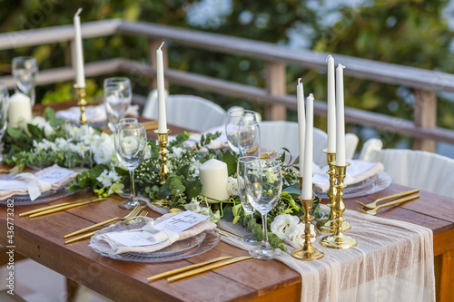 Romantic Wedding Table Top Layout Table Spread with flowers no people with gold cutlery white table cloth and scenic view of sunset and blue skies with copy space tablescape