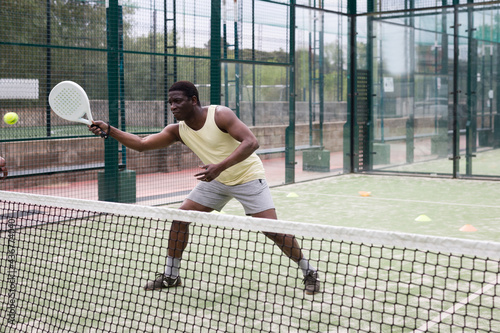 Young adult man playing paddle tennis with partners at warm sunny day, healthy lifestyle concept © JackF