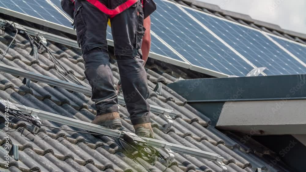 Slow motion shot of male technician screwing rail on rooftop for solar panels Slow motion shot of male technician screwing rail on rooftop for solar panels