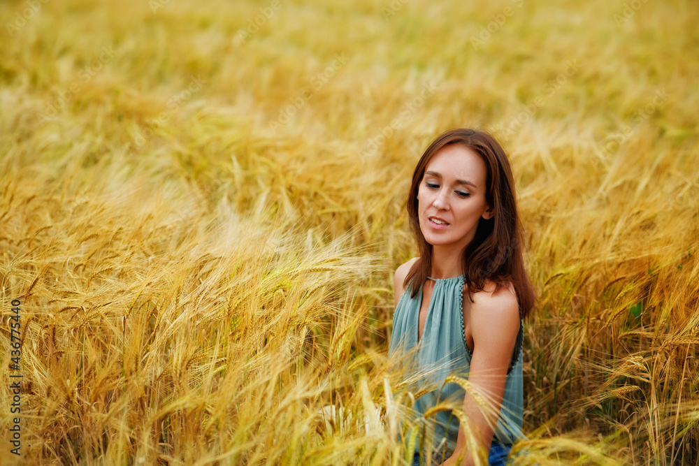 Close-up portrait of a happy smiling woman sitting in a wheat field. Rural summer landscape Close-up portrait of a happy smiling woman sitting in a wheat field. Rural summer landscape
