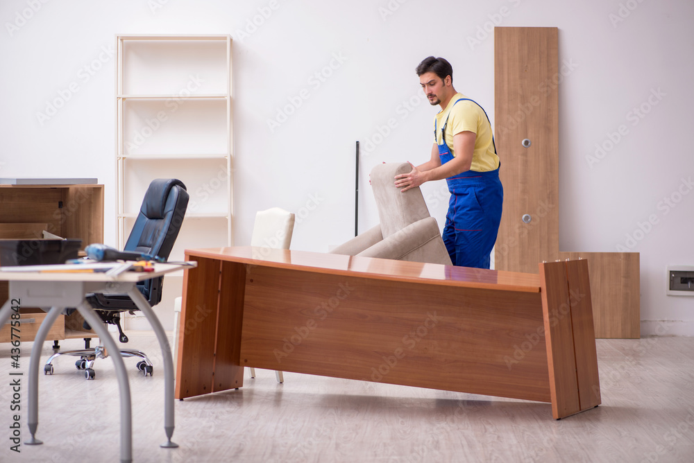 Young male carpenter repairing arm-chair in the office