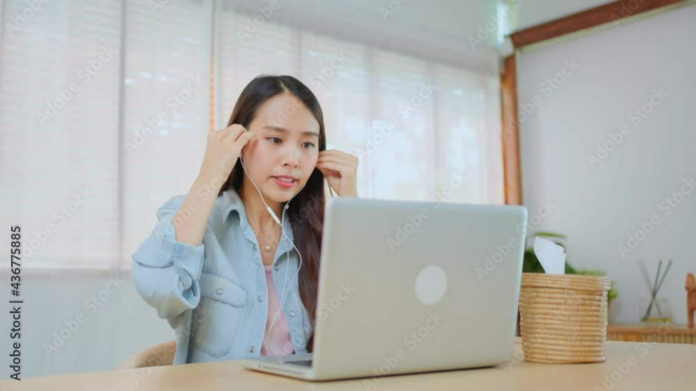 Happy beautiful girl put on earphone and watch movie on laptop at home