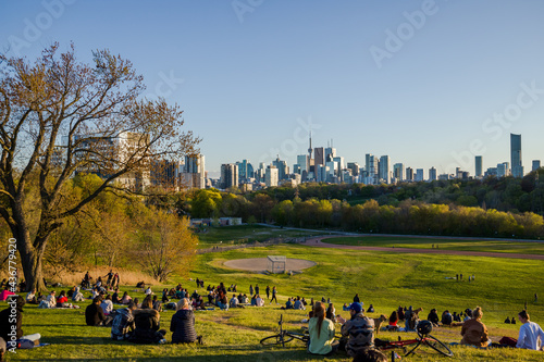 Downtown Toronto Canada panoramic cityscape skyline view over Riverdale Park in Ontario. people sit on grass. Picnic outside. sunset time photo