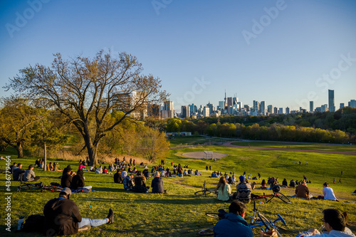 Downtown Toronto Canada panoramic cityscape skyline view over Riverdale Park in Ontario. people resting on grass. Picnic outside. sunset time