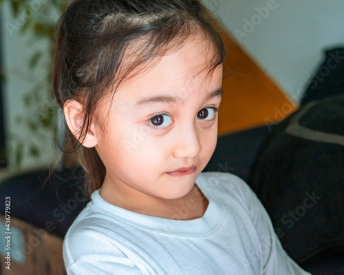 Portrait of little Asian baby girl with pony tail hair looking at camera, expression when learning at home.