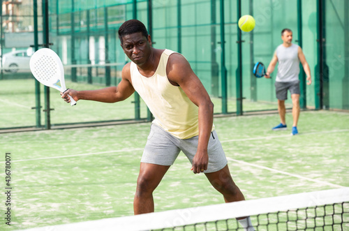 African american man and his partner playing paddle tennis on the padel court © JackF