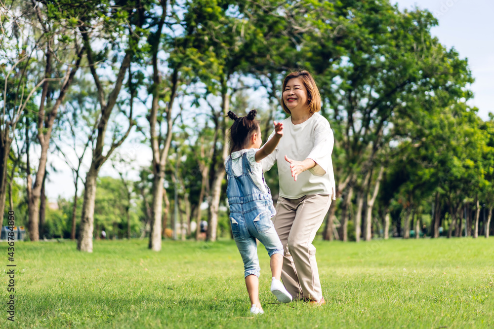 Portrait of happy asian grandmother and little asian cute girl enjoy relax in summer park.Young girl with their laughing grandparent smiling together.Family and togetherness